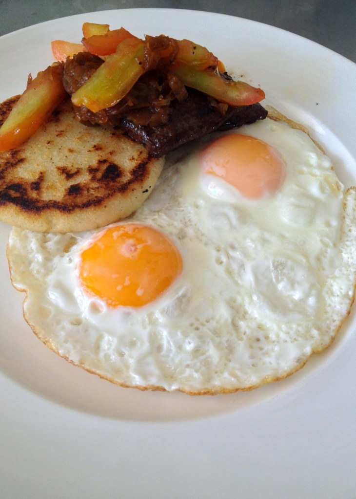 Steak and fried eggs with arepa